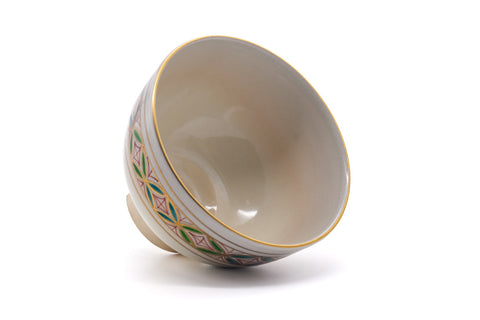 The chawan tilted to show its white glazed interior and gold rim.