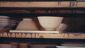 A single unglazed bowl resting on a glaze-spattered wooden kiln shelf