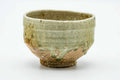 Earthy Shigaraki-yaki matcha chawan with a green celadon drip over warm stony clay, three-quarter view