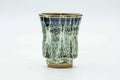 Slightly angled view of the tall drip-glazed yunomi showing the streaked glaze running down the body.