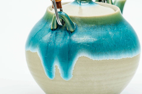 Closeup of the lid's navel knob and turquoise drip glaze over the cream Agano-yaki body