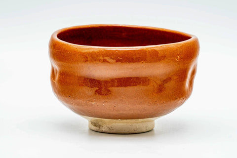 Three-quarter view of the glossy orange-red aka-raku chawan
