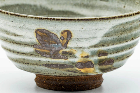 Close-up of the exterior highlighting the painted floral motif over the grey-white drip glaze.