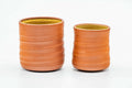 Pair of teacups, one larger and one smaller, with spiraling ridged orange clay exteriors, shown side by side.