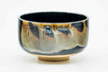 Dark hantsutsu-gata matcha chawan with a brown-beige drip glaze, three-quarter view