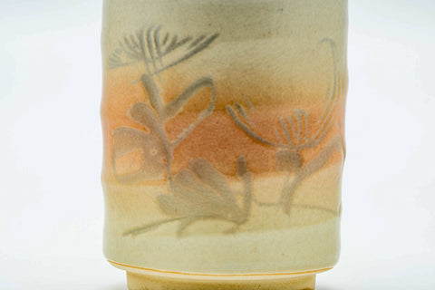 Close-up of a cup, showing the engraved floral decoration over the spiraling glaze.