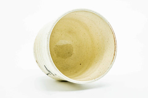 Teacup tilted to show the cream-glazed interior.
