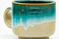 Close-up of a single cup, showing the turquoise glaze dripping over the beige body.