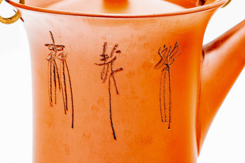 Closeup of the engraved calligraphy and bamboo motif on the body of the red shudei dobin