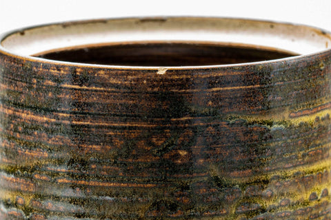 Closeup of the rim and upper body detailing the layered brown and beige glaze.