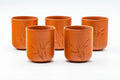 The five red yunomi cups arranged in a row, with engraved bamboo detailing.
