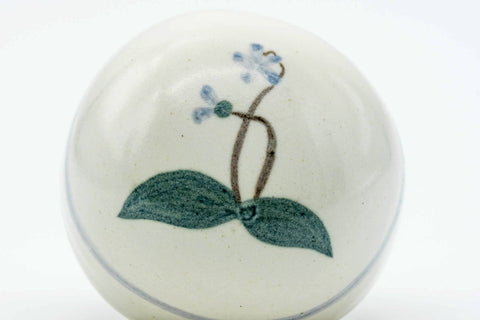 Overhead view of the lid showing the painted blue flower and green leaves.