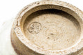 Underside of a cup showing the unglazed foot ring and an impressed maker's stamp.