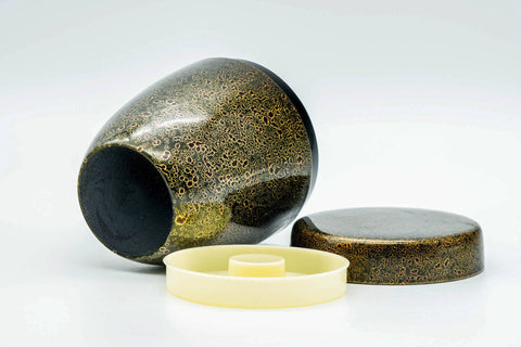 The canister tipped at an angle with the cream inner lid and outer lid set alongside.