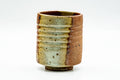 Shigaraki-yaki yunomi teacup with a wood-fired ash glaze over a ribbed orange body, front view.