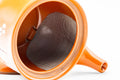 Interior view with the lid removed, revealing the built-in mesh strainer at the base of the spout.