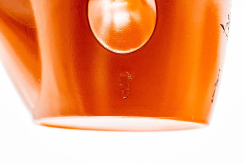 A single teacup on its side, showing the white-glazed interior against the red clay exterior.