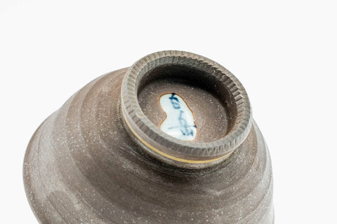 Tilted close-up into a cup, showing the green leaf motif and rim.