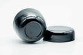 Glossy black-urushi matcha tea caddy, body lying on its side with the lid lying flat, showing the lid underside