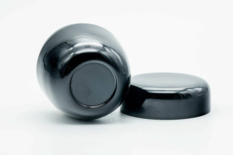 Glossy black-urushi matcha tea caddy, body lying on its side with the lid lying flat, showing the lid underside