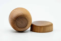 The wooden canister tipped to show its rounded base alongside the separate lid.