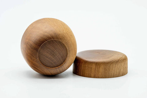 The wooden canister tipped to show its rounded base alongside the separate lid.
