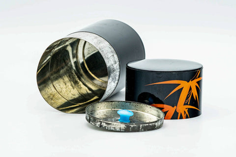 The canister opened to show the silvery metal interior, with the inner and outer lids set aside