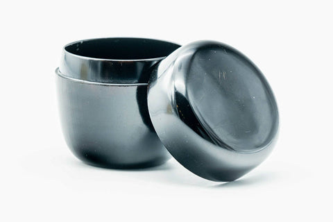 Small black-urushi ko-natsume matcha caddy, lid removed, body upright with black interior and the lid lying flat in front, three-quarter view
