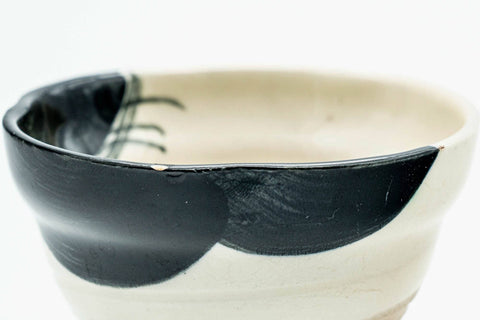 Profile view showing the bold black brushwork sweeping across the cup.