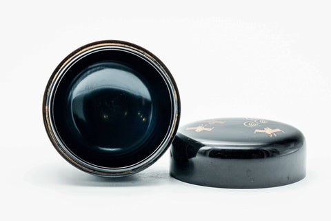 Black-lacquer soaring-bird matcha tea caddy, lid off, body upright with black interior and the lid lying beside, three-quarter view