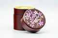 Dark maroon chazutsu tea canister with the lid removed, showing the pink and purple cherry-blossom decoration on the lid top