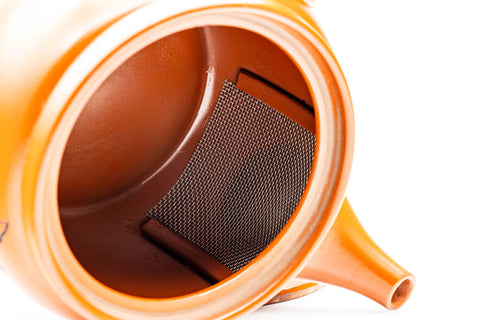 Overhead view looking into the open teapot, showing the interior and built-in ceramic mesh strainer.