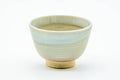 Front view of a Hagi teacup showing the muted cream-beige glaze and tapered form.