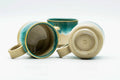 One cup tipped on its side, showing the side handle and foot.