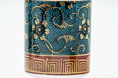Close-up of a cup's body, showing the blue glaze with gold florals and raised aochibu dots.