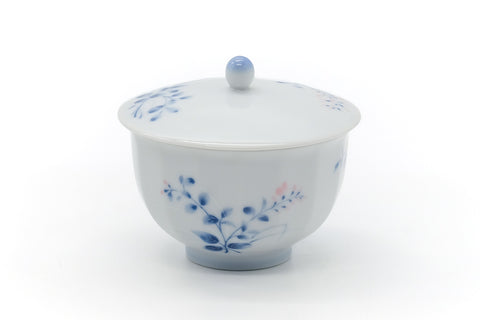 Three-quarter view of the lidded cup showing the blue floral motif.
