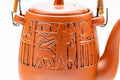 Elevated view looking down on the lid and arched top handle, with engraved motifs on the body.