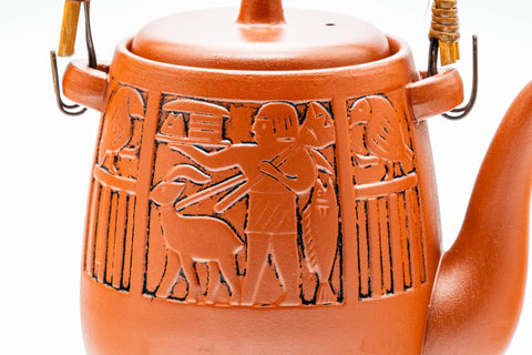 Elevated view looking down on the lid and arched top handle, with engraved motifs on the body.