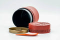 The tea canister opened to reveal the inner lid and dark interior, with the lid components beside it