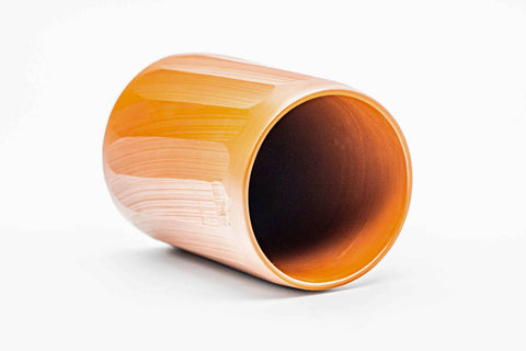 Teacup tilted to show the glossy red glazed interior.