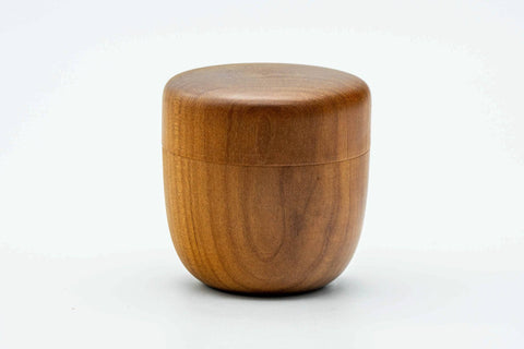 Side view of the closed wooden canister showing its tapered profile and grain.