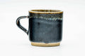 Side view of the handled cup with the handle to the left, showing the glossy near-black glaze.