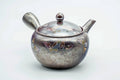 Large metallic-grey banko-yaki side-handle kyusu with a subtle floral motif, lid on, three-quarter view.