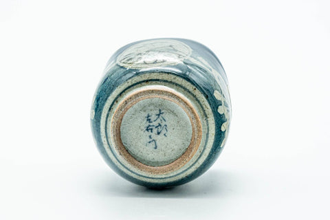 The cup tipped to show its foot and an impressed stamp.