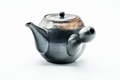 Side view showing the matte black glaze and brown drips running down the rounded body.