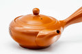 Three-quarter view of the red shudei Tokoname kyusu with lid on, showing the smooth orange clay and handle