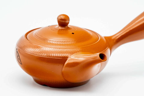 Three-quarter view of the red shudei Tokoname kyusu with lid on, showing the smooth orange clay and handle