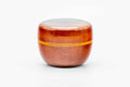 Small orange-amber lacquered ko-natsume tea caddy with a gold band, shown closed from the front.