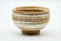 Brown matcha chawan with a milky white glaze band and spiral throwing rings, three-quarter view