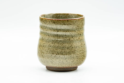 Side view of the beige speckled yunomi, highlighting the ribbed body and mottled cream-and-brown glaze.